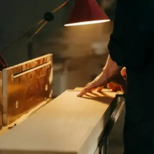 Carpintero inspeccionando una tabla de madera en el taller de Ferrenova, preparándola para el servicio de corte de madera.