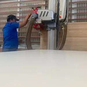 Operario de Ferrenova usando una escuadradora vertical para un servicio de corte de madera preciso en un tablero de melamina.