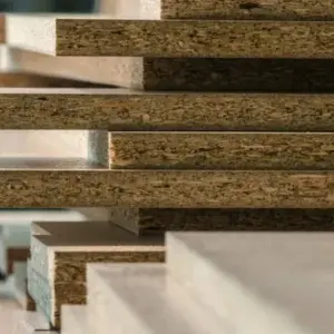 Piezas de tablero aglomerado apiladas después del servicio de corte de madera a medida en Ferrenova.