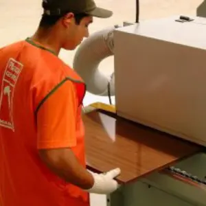 Operario de taller ingresando un tablero de melamina a una máquina calibradora, parte del Servicio de Corte y Enchapado de Ferrenova.