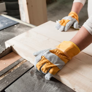 Operario guiando una tabla de madera para un Corte de Madera preciso en una sierra de mesa, un servicio ofrecido por Ferrenova.