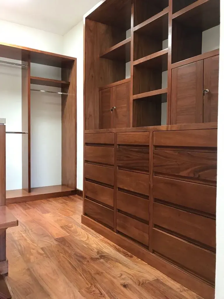 Interior de vestidor de madera con cajoneras y estantes, un proyecto modular realizado con el servicio de corte y enchapado de tableros de Ferrenova.