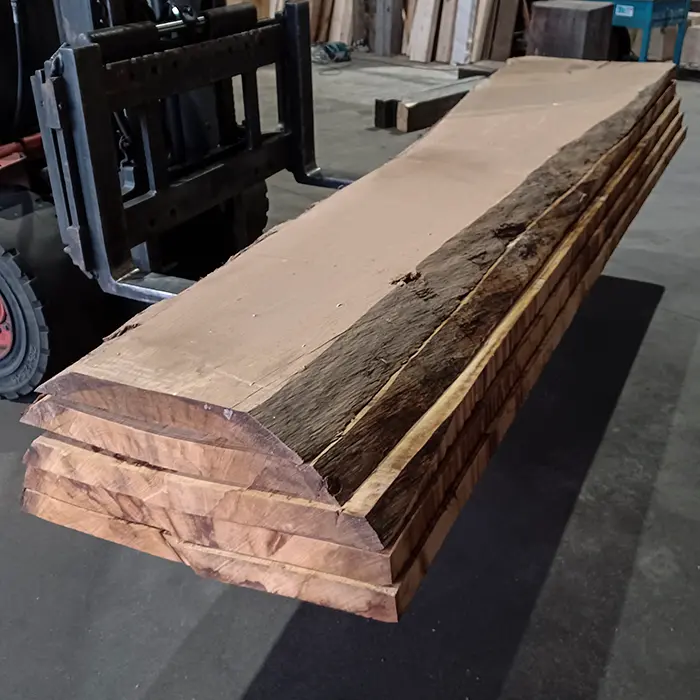 Grúa horquilla transportando una pila de tablones de madera a medida de roble macizo sin cantear en la bodega de Ferrenova.