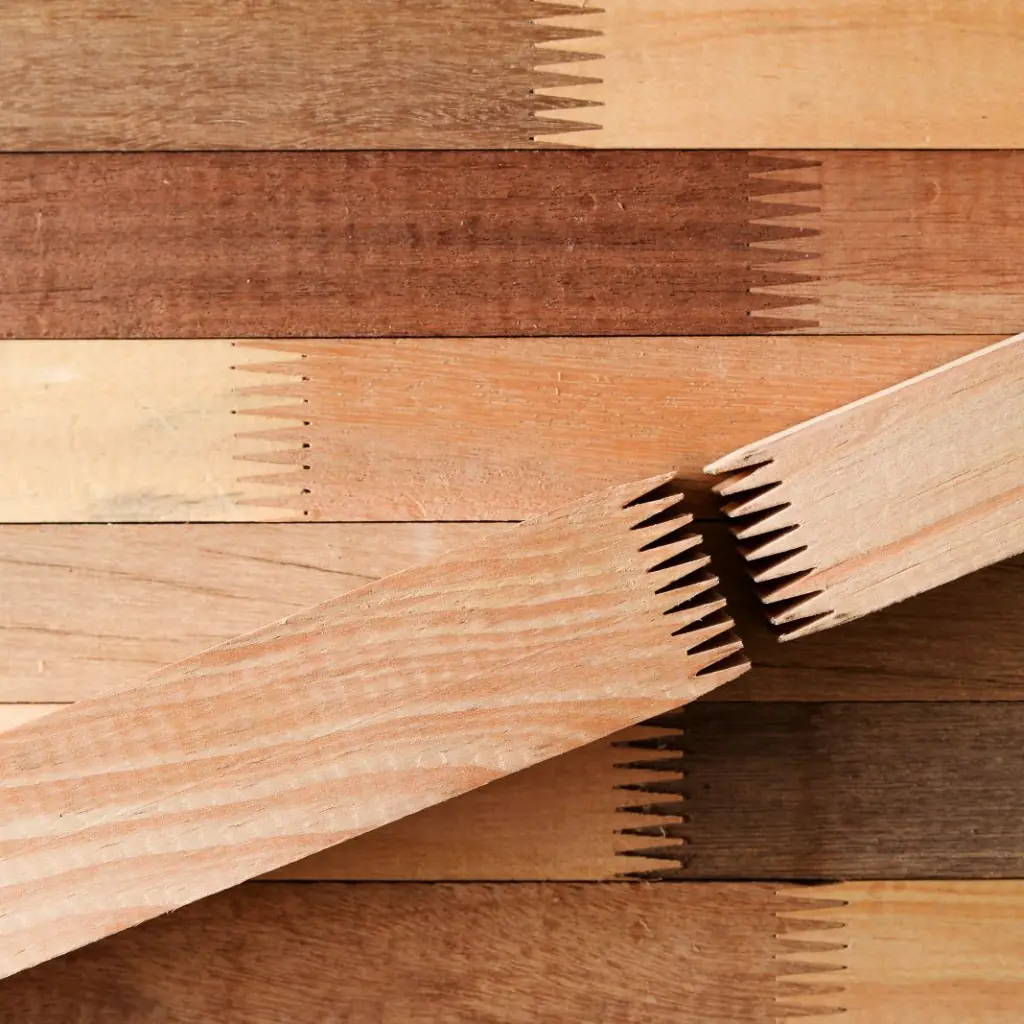 Detalle de la unión dentada (finger joint) en tablones de madera, ilustrando la exactitud requerida en los cortes de pino a medida.