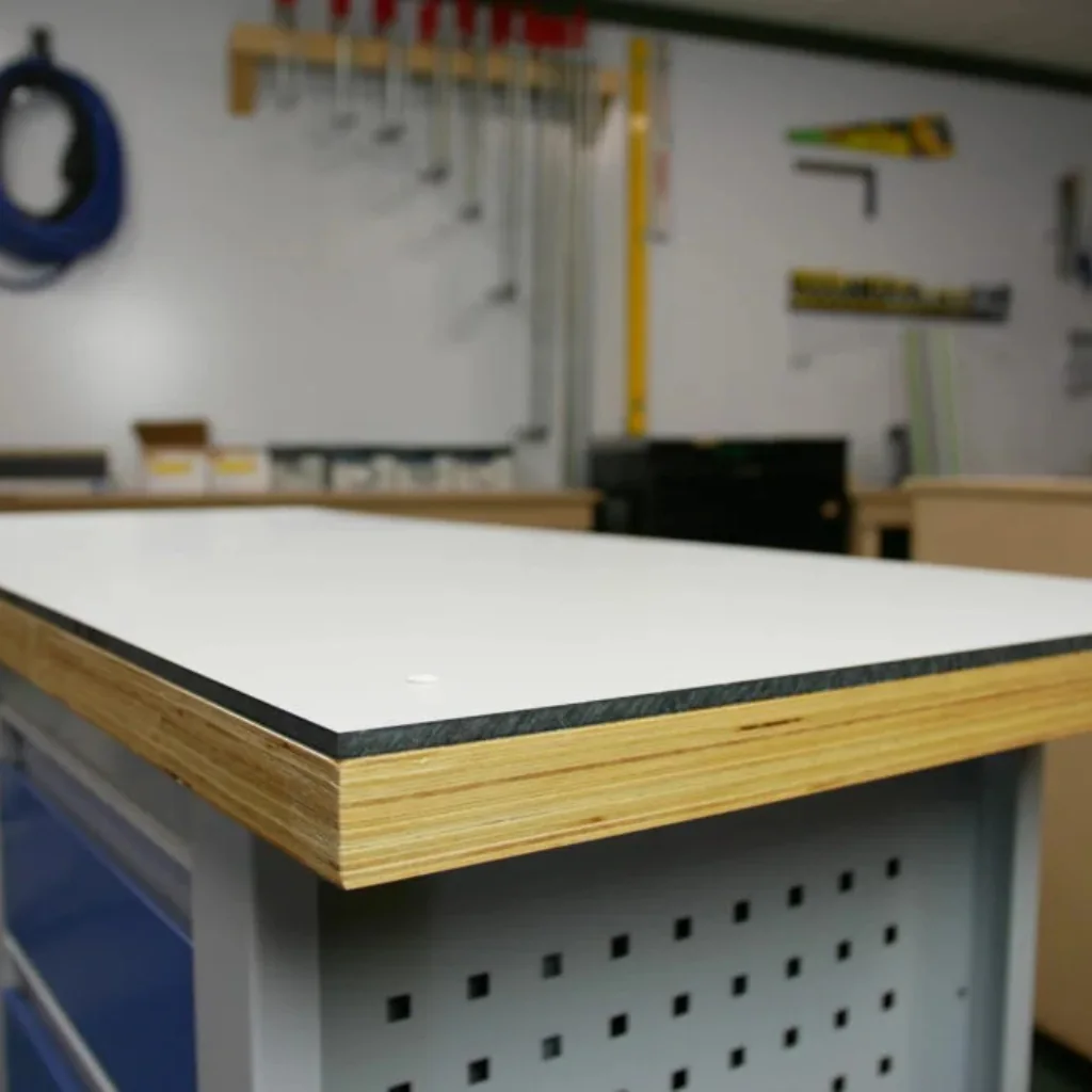 encimera HPL blanca instalada sobre tablero de contrachapado en banco de trabajo, mostrando canto laminado y acabado resistente en taller.